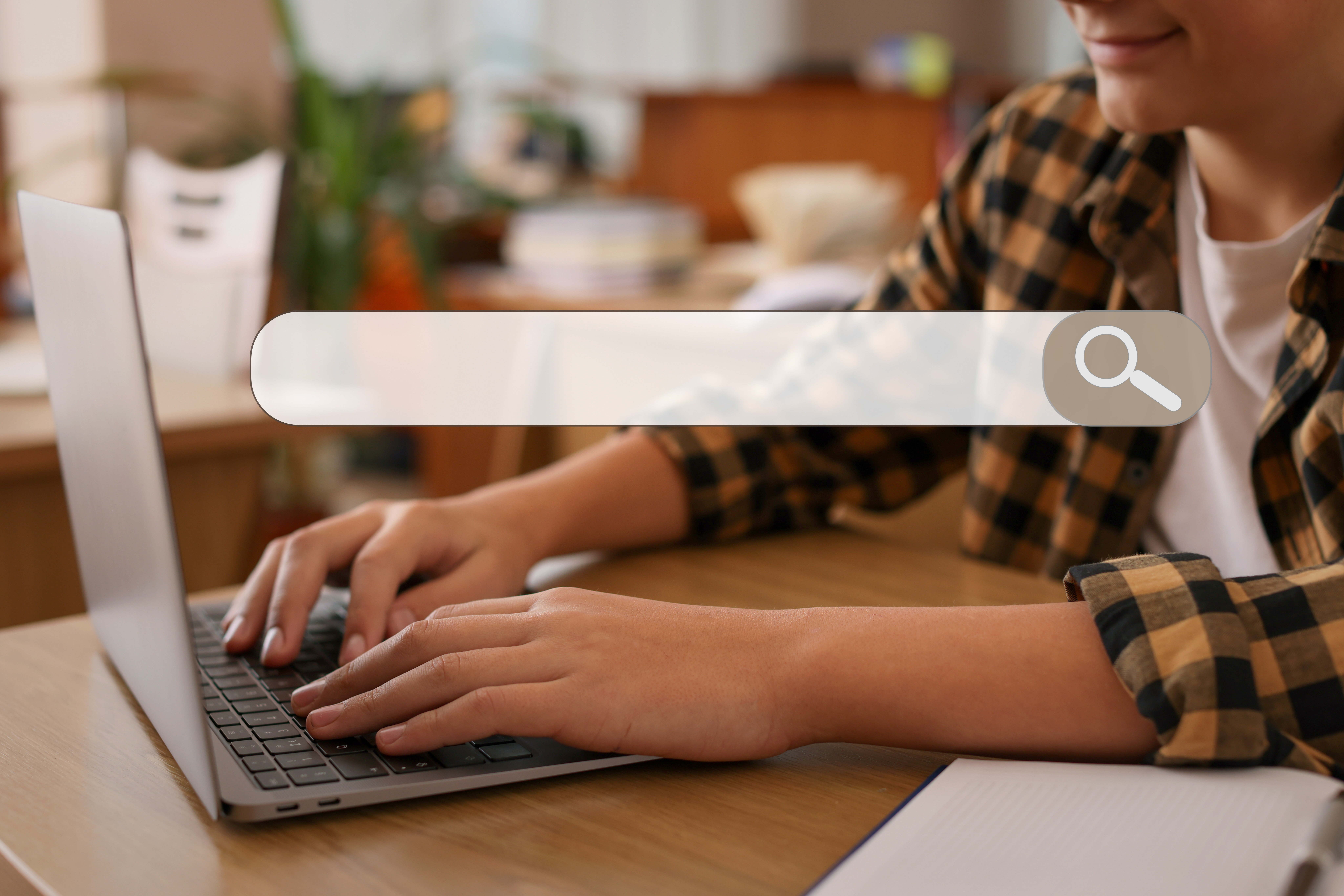 Search bar and teenage boy using laptop at desk. Closeup view